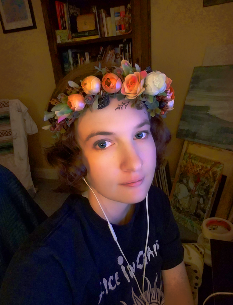 A photo of artist Samrae Duke.
They have a flower crown and an Alice In Chains t-shirt. Tat sums up their personality pretty decently.
